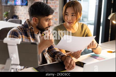 Asiatico maturo donna e giovane uomo revisione documenti in ufficio Foto Stock