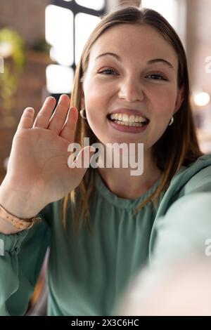 Giovane donna professionista caucasica in onde verdi in video chiamata con videocamera Foto Stock