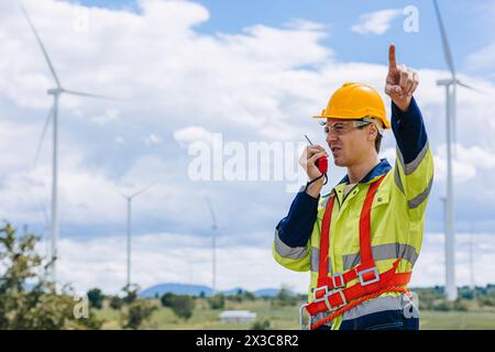 il controllo maschio dell'ingegnere opera sul campo manutenzione esterna del servizio generatore eolico. mano del lavoratore che punta la posizione al gesto dell'ordine Foto Stock