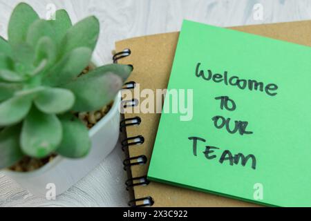 Concetto di benvenuto nel nostro team scrivete su appunti adesivi isolati su un tavolo di legno. Foto Stock