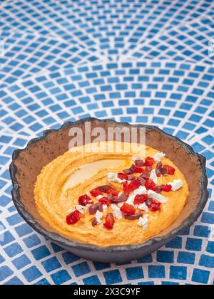 Htipiti, un antipasto greco a base di feta e peperoni rossi arrostiti, in una ciotola di ceramica, su un tavolo a mosaico blu e bianco, spazio copia superiore Foto Stock