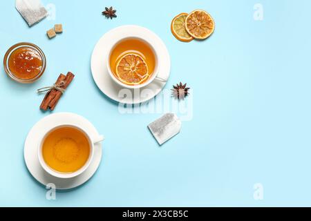 Due tazze di tè, marmellata e bastoncini di cannella su sfondo colorato Foto Stock