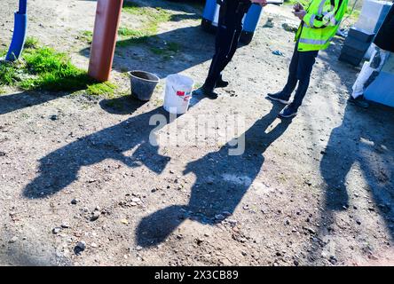 Garbsen, Germania. 23 aprile 2024. Un funzionario doganale (l) si trova presso un operaio edile durante un'ispezione del lavoro non dichiarato in una nuova area di costruzione nella regione di Hannover. Lo stato della bassa Sassonia, le dogane e le autorità locali hanno effettuato controlli mirati durante i giorni della campagna primaverile contro il lavoro sommerso. Credito: Julian Stratenschulte/dpa/Alamy Live News Foto Stock