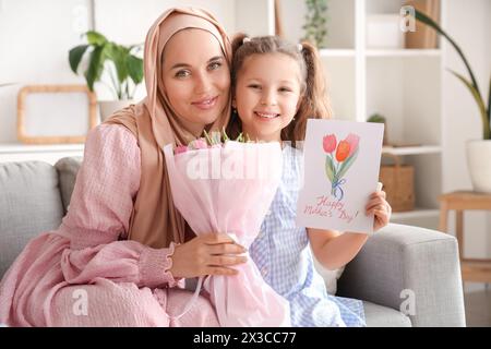 Bambina con regali e sua madre musulmana seduta sul divano a casa Foto Stock