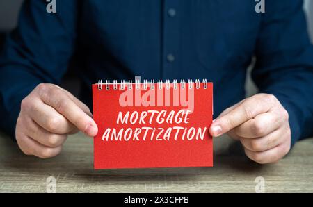 Concetto di ammortamento ipotecario. Processo di pagamento di un mutuo ipotecario attraverso pagamenti regolari nel tempo. Immobili e prestiti. Blocco note nelle mani di Foto Stock