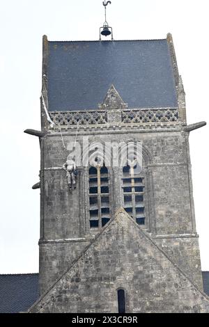 Questa fotografia scattata il 25 aprile 2024 mostra la chiesa di Sainte-Mere-Eglise, nel nord-ovest della Francia, dove è appeso un manichino raffigurante un paracadutista. Un paracadutista americano, John Marvin Steele 1912-1969, sbarcò sul pinnacolo della torre della chiesa a Sainte-Mere-Eglise, primo villaggio ad essere liberato dall'esercito degli Stati Uniti durante l'operazione Overlord il 6 giugno 1944. A giugno, la Francia terrà una cerimonia per celebrare il 80° anniversario degli sbarchi in Normandia del 1944, noti anche come sbarchi del D-Day lungo le spiagge della Normandia, un'operazione che ha gettato le basi della vittoria alleata sulla W Foto Stock
