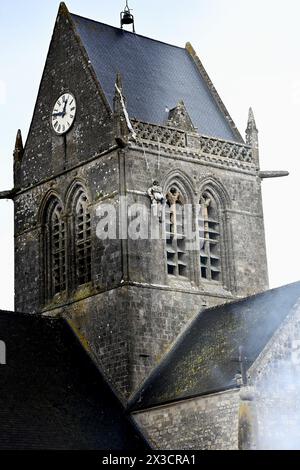 Questa fotografia scattata il 25 aprile 2024 mostra la chiesa di Sainte-Mere-Eglise, nel nord-ovest della Francia, dove è appeso un manichino raffigurante un paracadutista. Un paracadutista americano, John Marvin Steele 1912-1969, sbarcò sul pinnacolo della torre della chiesa a Sainte-Mere-Eglise, primo villaggio ad essere liberato dall'esercito degli Stati Uniti durante l'operazione Overlord il 6 giugno 1944. A giugno, la Francia terrà una cerimonia per celebrare il 80° anniversario degli sbarchi in Normandia del 1944, noti anche come sbarchi del D-Day lungo le spiagge della Normandia, un'operazione che ha gettato le basi della vittoria alleata sulla W Foto Stock