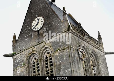 Questa fotografia scattata il 25 aprile 2024 mostra la chiesa di Sainte-Mere-Eglise, nel nord-ovest della Francia, dove è appeso un manichino raffigurante un paracadutista. Un paracadutista americano, John Marvin Steele 1912-1969, sbarcò sul pinnacolo della torre della chiesa a Sainte-Mere-Eglise, primo villaggio ad essere liberato dall'esercito degli Stati Uniti durante l'operazione Overlord il 6 giugno 1944. A giugno, la Francia terrà una cerimonia per celebrare il 80° anniversario degli sbarchi in Normandia del 1944, noti anche come sbarchi del D-Day lungo le spiagge della Normandia, un'operazione che ha gettato le basi della vittoria alleata sulla W Foto Stock