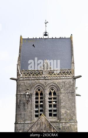 Questa fotografia scattata il 25 aprile 2024 mostra la chiesa di Sainte-Mere-Eglise, nel nord-ovest della Francia, dove è appeso un manichino raffigurante un paracadutista. Un paracadutista americano, John Marvin Steele 1912-1969, sbarcò sul pinnacolo della torre della chiesa a Sainte-Mere-Eglise, primo villaggio ad essere liberato dall'esercito degli Stati Uniti durante l'operazione Overlord il 6 giugno 1944. A giugno, la Francia terrà una cerimonia per celebrare il 80° anniversario degli sbarchi in Normandia del 1944, noti anche come sbarchi del D-Day lungo le spiagge della Normandia, un'operazione che ha gettato le basi della vittoria alleata sulla W Foto Stock