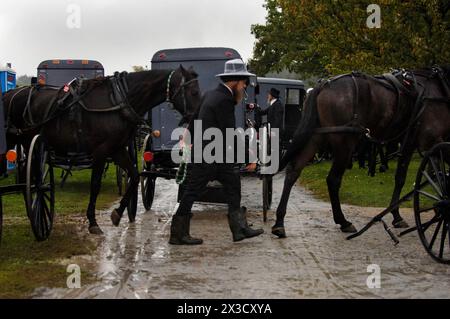 Un uomo Amish cammina dall'altra parte della strada vicino a un buggy in una casa di una delle vittime uccise in una scuola Amish a NIC Foto Stock