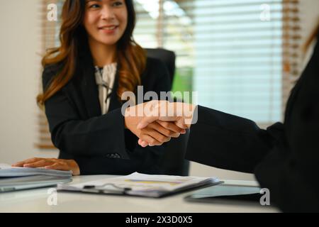 Colpo ritagliato di uomini d'affari che stringono la mano dopo aver firmato un contratto o concluso con successo le trattative Foto Stock