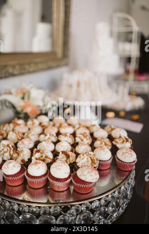 Eleganti cupcake in velluto rosso su un piedistallo a specchio. Foto Stock