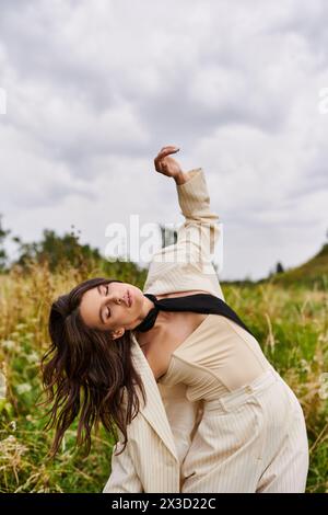 Una bella giovane donna con un abito bianco e una cravatta nera che si gode la brezza estiva in campo. Foto Stock