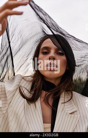 Una giovane donna elegante con un abito si trova in un campo, tenendo in mano un ombrello mentre ama la brezza estiva. Foto Stock