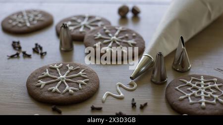 Glassa artistica con fiocchi di neve sui biscotti di pan di zenzero delle vacanze Foto Stock