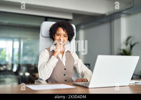 Giovane afroamericana sicura di sé, felice, seduta alla scrivania dell'ufficio, ritratto. Foto Stock