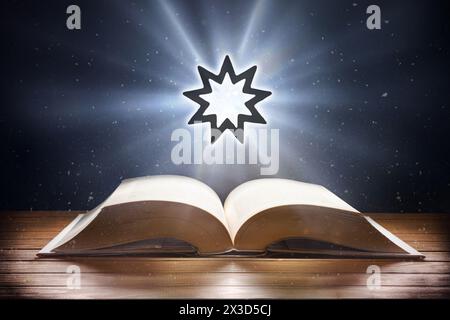 Libro aperto su tavolo in legno e simbolo bahai con fascio di luce su sfondo scuro. Vista frontale. Foto Stock