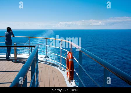 Persona sul ponte della nave che guarda all'orizzonte Foto Stock