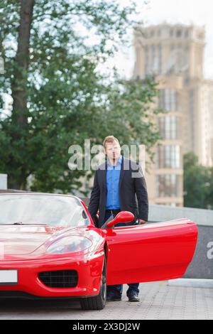 MOSCA, RUSSIA - 22 giugno 2016: Uomo d'affari di successo (con versioni di modelli) al volante di una Ferrari rossa di lusso Foto Stock