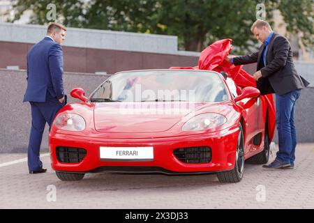 MOSCA, RUSSIA - 22 giugno 2016: Due uomini d'affari di successo (con versioni di modelli) che si accingeranno a guidare una supercar rossa di lusso Ferrari Foto Stock