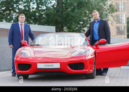 MOSCA, RUSSIA - 22 giugno 2016: Due uomini d'affari maturi (con versioni di modelli) all'esterno accanto alla lussuosa supercar Ferrari Foto Stock