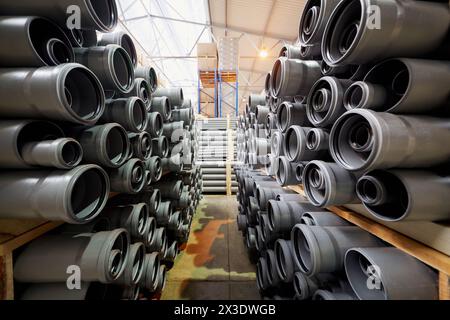 Confezioni di tubi in plastica e scatole di cartone sugli scaffali del magazzino di fabbrica. Foto Stock