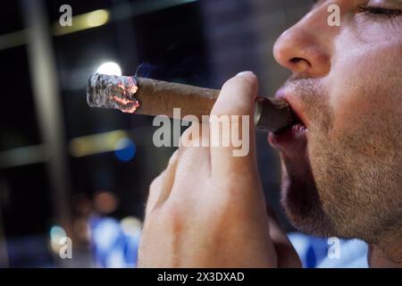 Faccia di profilo dell'uomo che fuma sigaro. Foto Stock