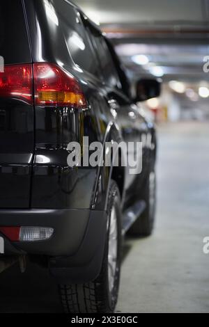 Lato destro dell'auto nera nel parcheggio sotterraneo, vista posteriore. Foto Stock