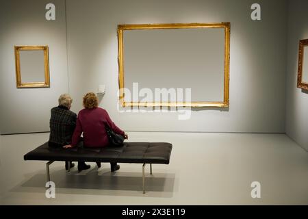 Due donne siedono sul divano in camera con cornici alle pareti. Foto Stock