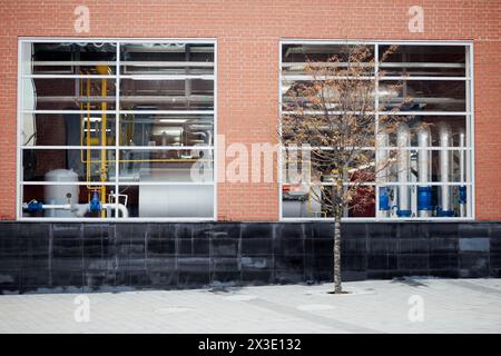 Grandi finestre in muratura di mattoni rossi e attrezzature industriali dietro di essa. Foto Stock