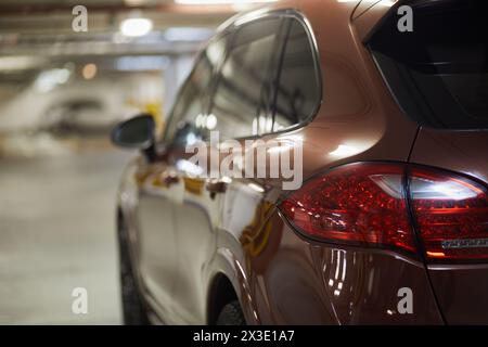 Luci di posizione posteriori e lato conducente dell'auto moderna presso il parcheggio sotterraneo, poco profondo dof. Foto Stock