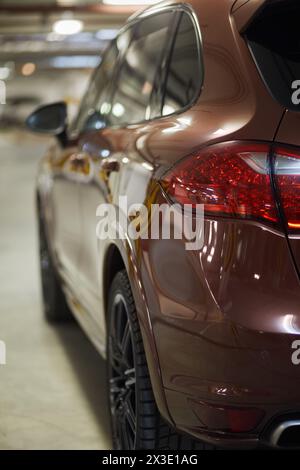 Luce di posizione posteriore sinistra e lato conducente dell'auto moderna nel parcheggio sotterraneo, poco profondo dof. Foto Stock