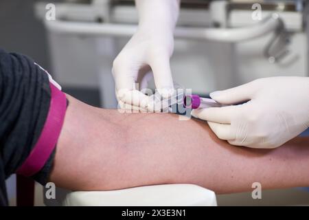 L'infermiere di laboratorio preleva sangue con capsula sottovuoto per il test dalla vena del braccio in laboratorio. Foto Stock