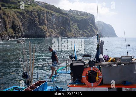 Un pescatore portoghese scende a bordo della sua barca ormeggiata in una banchina della costa meridionale, il 18 aprile 2024, a Ribeira Brava, Madeira, Portogallo. Foto Stock