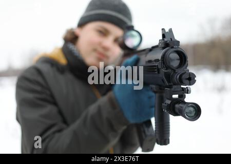 Teenager con pistola prende la mira durante la partita laser all'aperto in inverno, concentrandosi sulla museruola Foto Stock