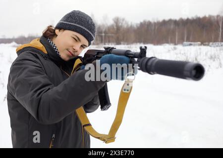 Teen with gun prende la mira durante il gioco laser all'aperto in inverno Foto Stock