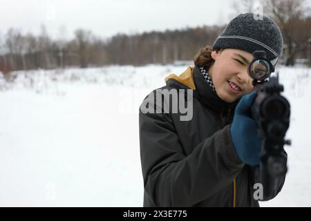 Teenager con pistola prende la mira durante la partita laser all'aperto in inverno Foto Stock