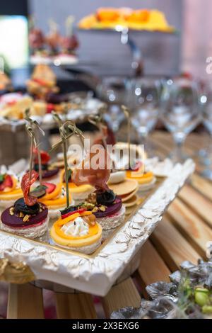 Deliziose prelibatezze e spuntini su un tavolo per eventi con catering con sfondo sfocato, che offre delizie culinarie. Foto Stock