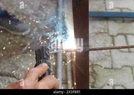 Uomo che lavora alla saldatura del ferro in cantiere. Primo piano. Foto Stock