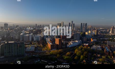 L'immagine mostra una vista aerea mozzafiato dello skyline di una città inondata dalle calde sfumature di un sole che tramonta, mettendo in risalto grattacieli e archi urbani Foto Stock