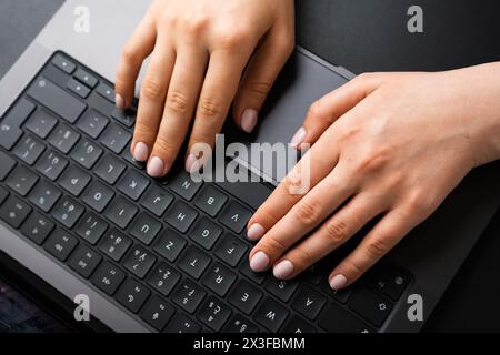 BERLINO, GERMANIA - 14 APRILE 2024: Donne che digitano le mani sulla tastiera del laptop, vista dall'alto. Foto Stock