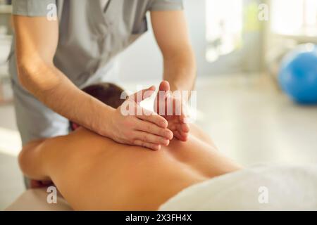 Lo specialista del massaggio maschile sta facendo un massaggio professionale, terapeutico e rilassante alla schiena Foto Stock