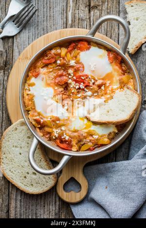 Shakshuka con uova pomodoro e prezzemolo in una padella di ghisa. Foto Stock