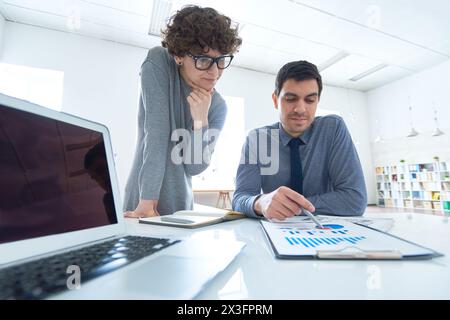 Colleghi professionali che guardano i grafici e trovano una soluzione aziendale Foto Stock