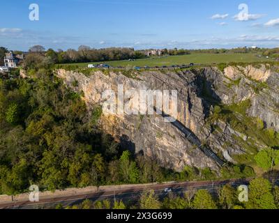 Cattura con droni di una cava di pietra calcarea panoramica accanto a una strada con campi lussureggianti e case sullo sfondo Foto Stock
