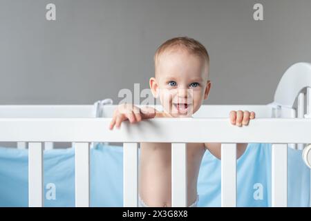 Bambino ridendo che si allontana dalla sua culla Foto Stock