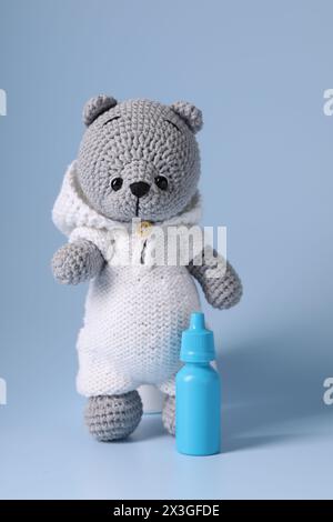 Orsetto giocattolo e spray nasale su sfondo azzurro Foto Stock