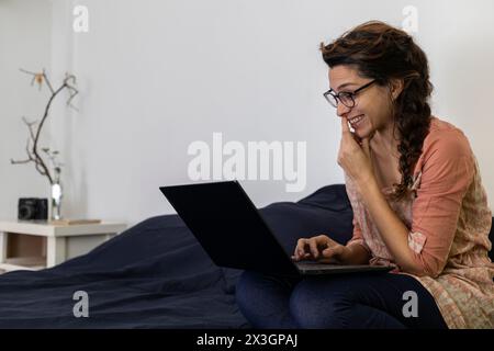 Stanza di una giovane donna latinoamericana sorridente durante una videochiamata Foto Stock