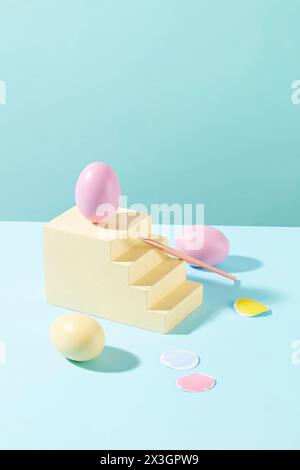 Uovo di Pasqua rosa pastello posto su una scala gialla con un pennello appoggiato. Vengono visualizzati pochi pezzi di carta con colori di vernice. Pasqua è una Chr Foto Stock