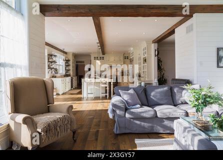 Divano modello ektorp imbottito grigio scuro, poltrona bergere nel soggiorno con tappeto e pavimenti in legno di quercia macchiato all'interno di casa in stile country, Quebec Foto Stock